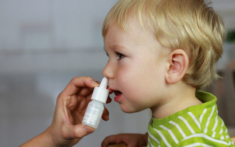 Khi dùng thuốc xịt rửa mũi, cần cho trẻ ngồi dậy để dịch mũi tuôn sạch ra ngoài.