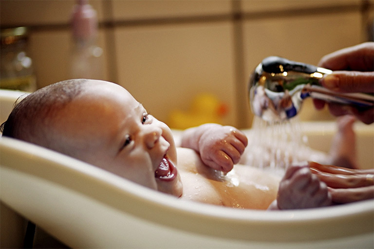 Cha mẹ tắm nước ấm cho trẻ để hạ sốt và mang lại cảm giác thoải mái khi trẻ bị sốt do bị viêm amidan